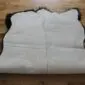 Large quad sheepskin rug with thick cream wool and dark brown edges on a wooden floor.
