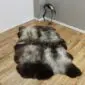Large quad sheepskin rug with natural grey, cream and dark brown mottled wool on a wooden floor.