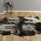 Large quad sheepskin rug with natural grey, cream and dark brown wool on a wooden floor.