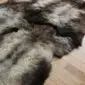 Close up of a quad sheepskin rug with long, thick wool in mottled shades of grey, cream and dark brown.