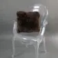 Square dark brown sheepskin cushion with long, curly wool texture placed on a acrylic .