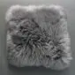 Square grey sheepskin cushion with long, thick wool texture.