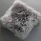 Square grey sheepskin cushion with long, textured wool pile.