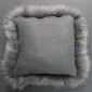 Square grey sheepskin cushion with a suede-effect centre and long, fluffy wool trim around the edges.