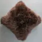 Square natural brown sheepskin cushion with long, curly wool texture.