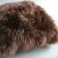Square natural brown sheepskin cushion with long, thick curly wool texture.