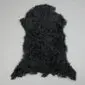 Black Tibetan lambskin rug with long, curly wool and an irregular natural shape.