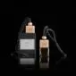 Two square glass car air freshener bottles with wooden lids and black hanging cords .