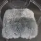 Square steel grey sheepskin seat pad with thick, textured wool pile on a .
