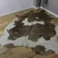 Natural brown and white cowhide rug with gold metallic splatters and an irregular shape.