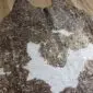 Natural brown and white cowhide rug with metallic gold speckles and irregular edges.