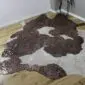 Natural shaped cowhide rug with brown and white patches and rose gold metallic splatters on a wooden floor.