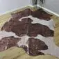 Natural shaped cowhide rug with brown and white patches and metallic rose gold splatters.