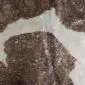 Close-up of a brown and white cowhide rug with metallic pink gold speckles.