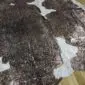 Natural brown and white cowhide rug with metallic rose gold splatters and an irregular shape.