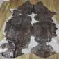 Natural shaped cowhide rug with dark brown and white patches featuring rose gold metallic speckles.