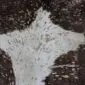 Close-up of a brown and white cowhide rug with rose gold metallic splatters.