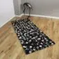 Rectangular patchwork cowhide rug featuring a grid of black and grey squares on a wooden floor.