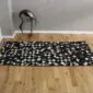 Rectangular patchwork cowhide rug featuring a grid of black and white squares on a wooden floor.