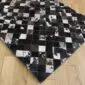 Patchwork cowhide rug featuring a grid of black, grey, and white squares with natural hair-on texture.