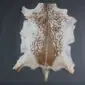 Natural goatskin rug with white edges and a speckled brown and tan centre pattern.