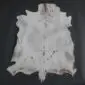 Natural goatskin rug with grey and white fur featuring dark grey spots and an irregular shape.