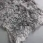 Close-up of a natural grey sheepskin rug with thick, curly wool texture.