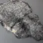 Natural grey curly sheepskin rug with a textured, woolly surface and irregular organic shape. detail view