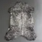 Natural grey curly sheepskin rug with a textured, woolly surface and organic shape.