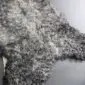 Close-up of a natural grey curly sheepskin rug with textured wool locks.