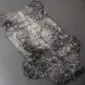 Natural grey curly sheepskin rug with a textured, woolly surface and irregular organic shape.