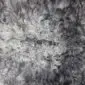 Close-up of a natural grey curly sheepskin rug showing dense, textured wool spirals.