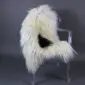 Natural white Icelandic sheepskin rug with long curly wool and a single black spot, laid flat.