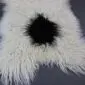 Natural white curly Icelandic sheepskin rug featuring a large, central black spot and long textured wool.