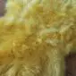 Close-up of a bright yellow sheepskin rug with thick, textured wool fibres.