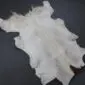 Goatskin Rug GS914c Natural goatskin rug with cream and grey fur and a small brown patch on a dark grey background.