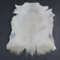 Natural goatskin rug with short white and grey fur, featuring an irregular organic shape and long hair at the bottom edge.