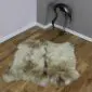 Large double rare breed sheepskin rug with long cream and grey mottled wool on a wooden floor.