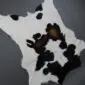 Natural-shaped calfskin rug featuring a white base with large black and brown spots.