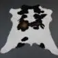 Natural calfskin rug with white fur and irregular black and brown patches.