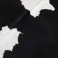 Close-up of a black and white cowhide rug showing natural hair texture and organic patterns.