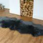 Sheepskin-Double-Grey-c Long, dark grey double sheepskin rug with a thick, textured wool pile on a wooden floor. detail view