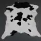 Natural calfskin rug with a black and white speckled pattern and irregular organic shape.