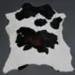 Natural calfskin rug with a white base and large black and dark brown spots.