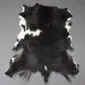 Natural goatskin rug with a black and white patterned hide and irregular edges.