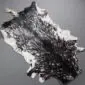 Natural goatskin rug with a mottled black and white pattern and irregular edges.