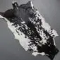 Natural goatskin rug with a mottled black and white pattern and irregular edges.