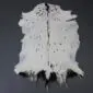 Natural white goatskin rug with a dark brown dorsal stripe and small brown speckles.