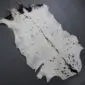 Natural goatskin rug with white fur, black spots and a dark grey spine stripe.