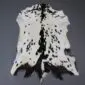 Natural goatskin rug with white fur and black speckled markings, featuring a dark central stripe and irregular edges.
